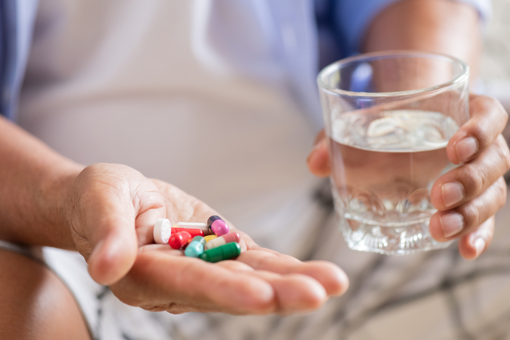 A man with pills of Naltrexone and glass of water in his hands.