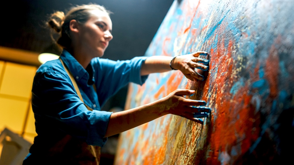 Lady in blue long sleeve in addiction recovery creating painting using hands