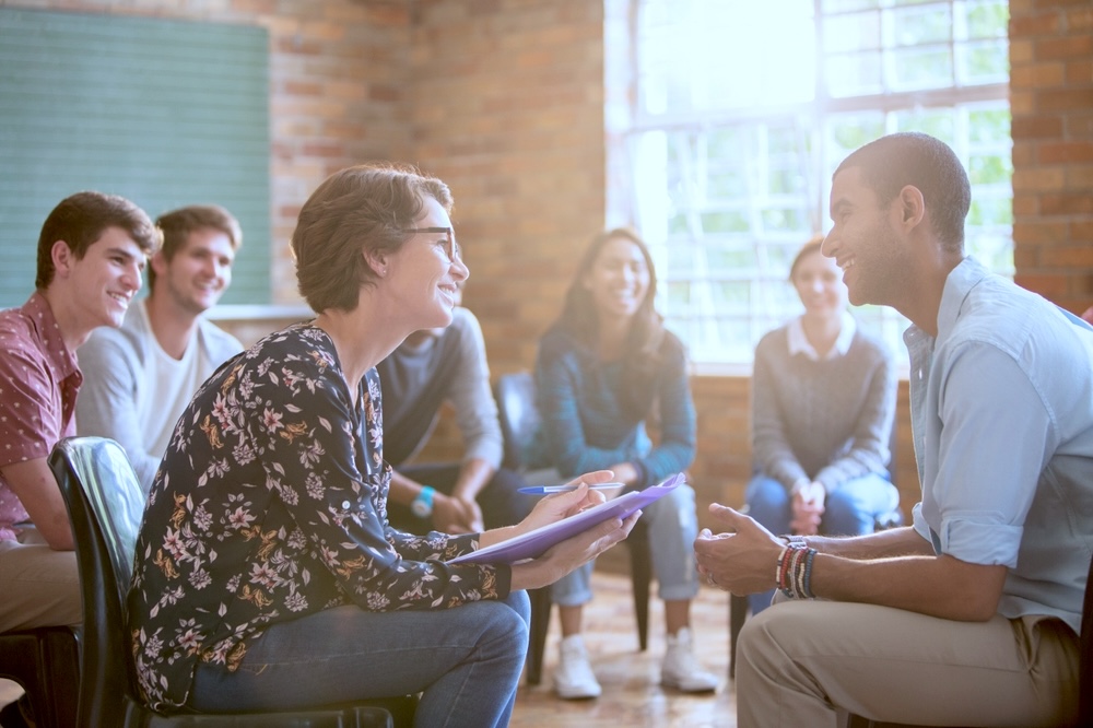 Group watching man and woman talking in group therapy session