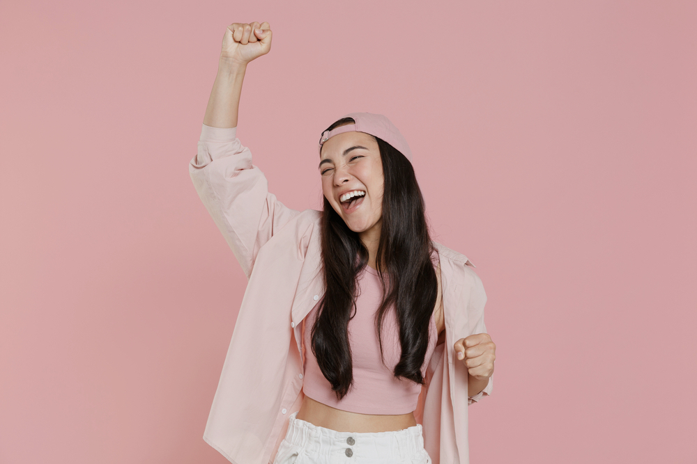 A joyful woman in pink background who is in addiction recovery