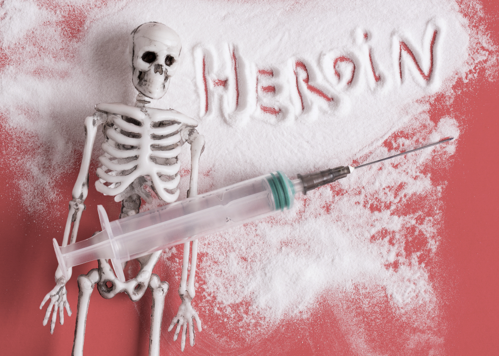 Heroin and a human skeleton with a syringe on the background of scattered heroin