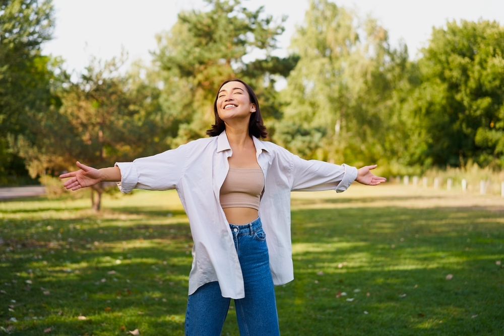 A happy woman in a park who is in addiction recovery